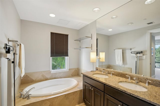 bathroom featuring a garden tub, double vanity, a sink, and visible vents