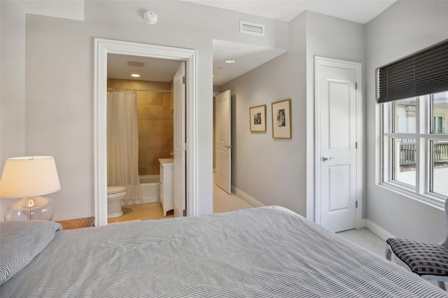 bedroom featuring light colored carpet, visible vents, baseboards, and ensuite bathroom