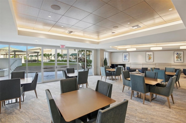 dining space featuring light colored carpet, a raised ceiling, and visible vents