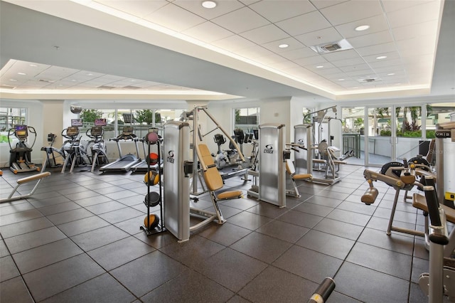 gym with a raised ceiling, a drop ceiling, and visible vents