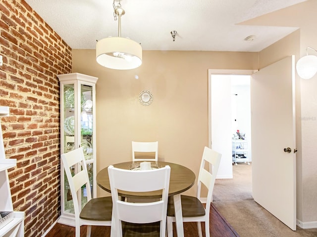 carpeted dining area with brick wall