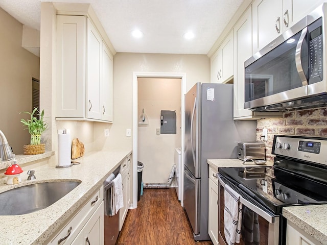 kitchen featuring dark wood-type flooring, stainless steel appliances, sink, and light stone countertops