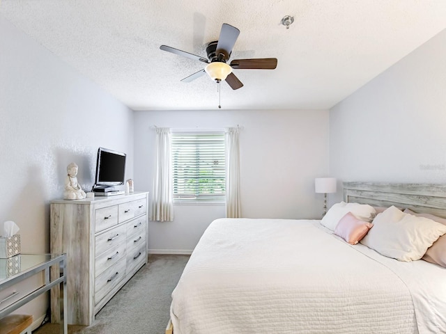 carpeted bedroom featuring ceiling fan and a textured ceiling