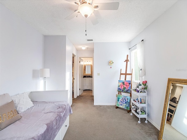 bedroom featuring a textured ceiling, ceiling fan, light carpet, and ensuite bathroom