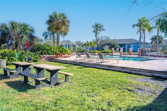 view of property's community featuring a swimming pool, a lawn, and a patio area