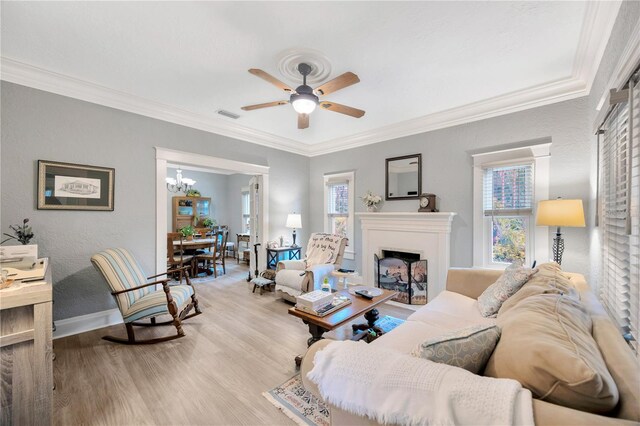 living room with light wood-type flooring, ceiling fan with notable chandelier, and crown molding