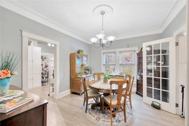 dining area with crown molding, a textured ceiling, an inviting chandelier, and light hardwood / wood-style floors