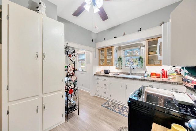 kitchen with a healthy amount of sunlight, stainless steel range oven, white cabinets, and sink