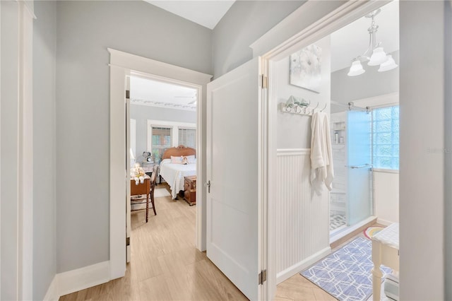 hallway with light hardwood / wood-style flooring and a chandelier