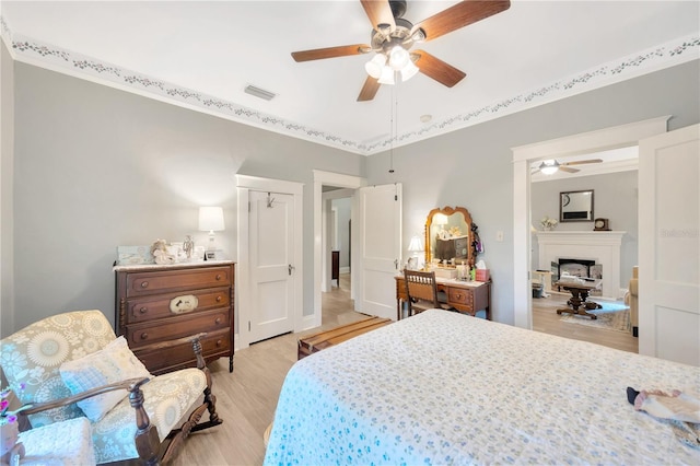 bedroom featuring ceiling fan, crown molding, and light hardwood / wood-style flooring