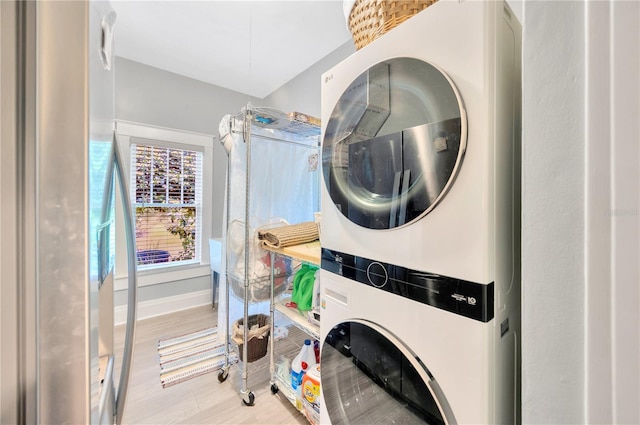 laundry room with light wood-type flooring and stacked washer / dryer