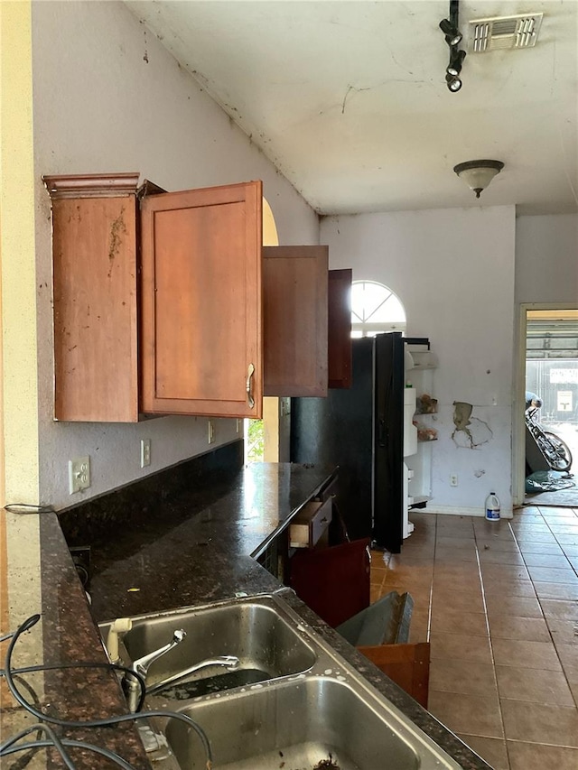 kitchen with black fridge, tile patterned flooring, track lighting, and sink