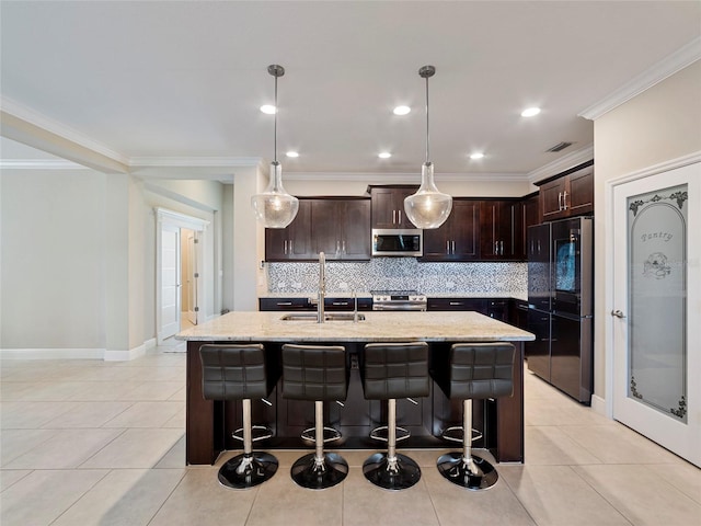 kitchen with decorative light fixtures, stainless steel appliances, light stone counters, sink, and decorative backsplash