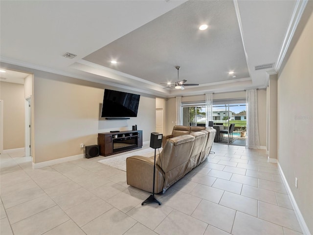 living room with a raised ceiling, ceiling fan, and light tile patterned floors