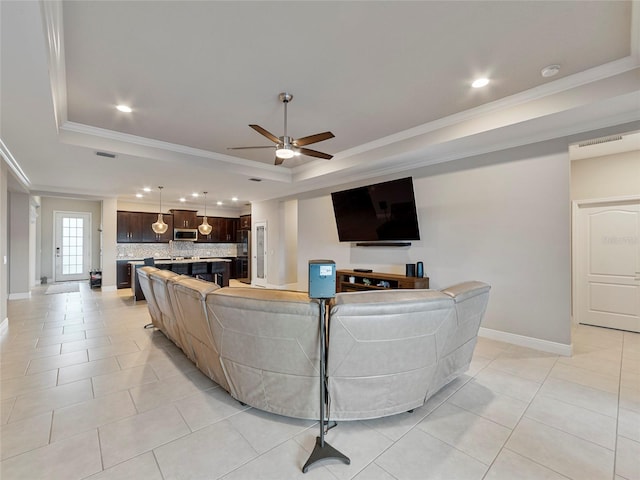 living room featuring ceiling fan, light tile patterned floors, a raised ceiling, and ornamental molding