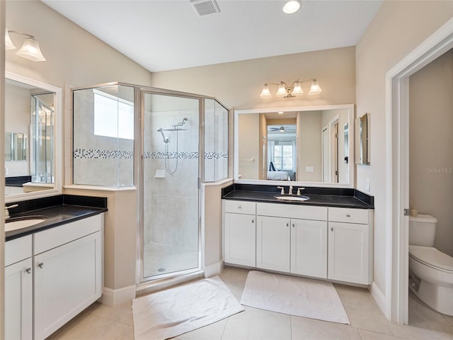 bathroom featuring tile patterned flooring, vanity, toilet, and walk in shower