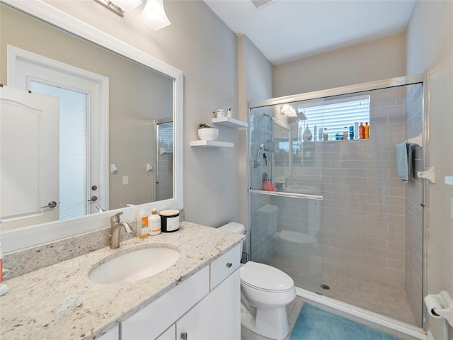 bathroom featuring tile patterned flooring, vanity, toilet, and walk in shower