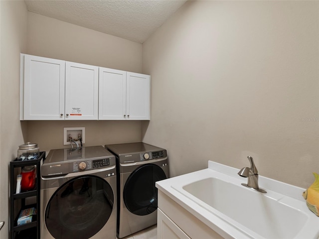 washroom with washing machine and clothes dryer, cabinets, sink, and a textured ceiling