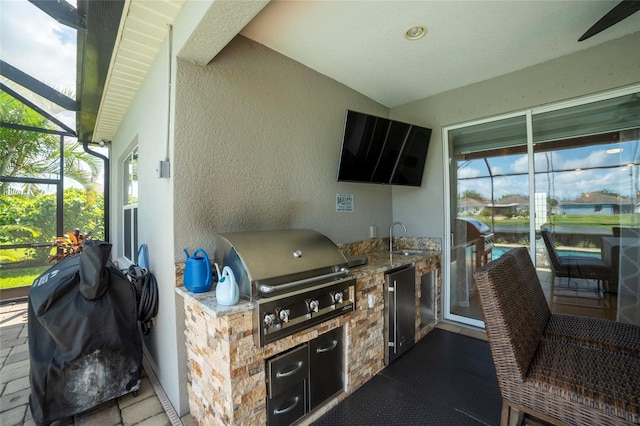 view of patio featuring glass enclosure, sink, and a grill