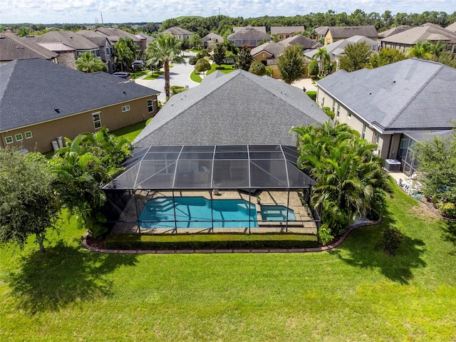 view of pool with glass enclosure and a lawn