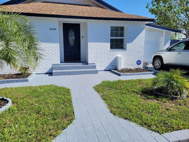 2503 W Marquette Ave, Tampa, FL 33614 - view of front of home featuring brick siding, an attached garage, roof with shingles, and entry steps