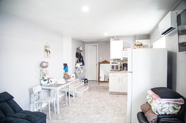 kitchen featuring an AC wall unit, white refrigerator, and white cabinetry