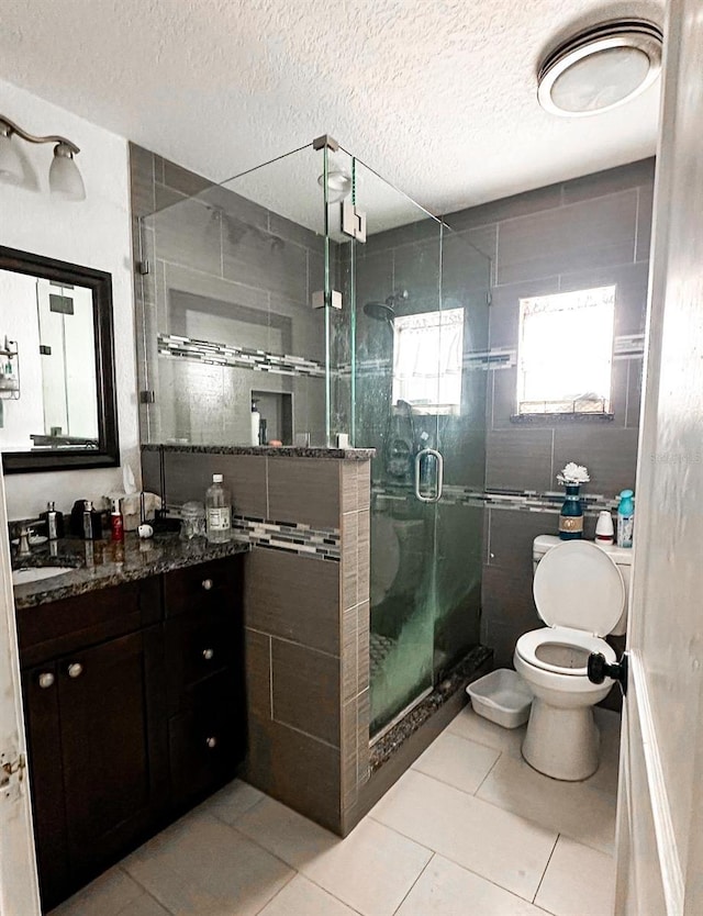 bathroom featuring a textured ceiling, vanity, an enclosed shower, tile patterned flooring, and toilet