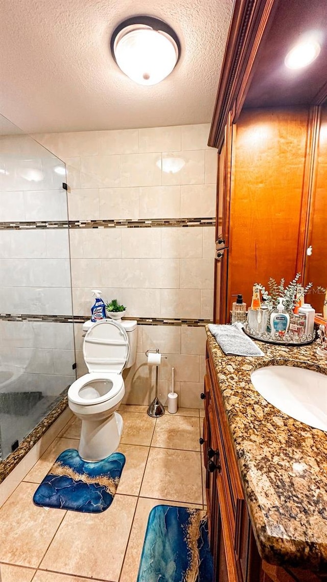 bathroom featuring tile patterned flooring, an enclosed shower, toilet, vanity, and a textured ceiling