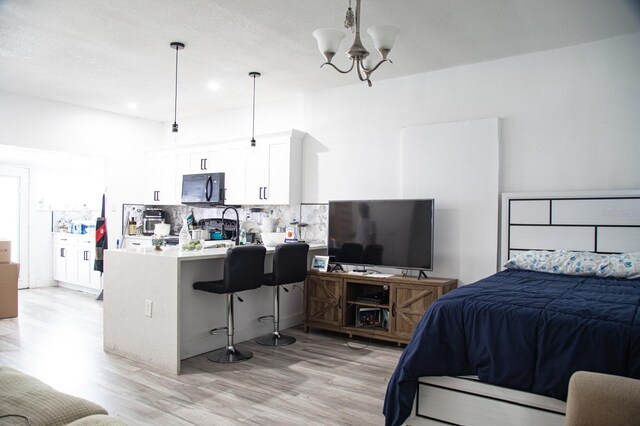 bedroom with a chandelier, a textured ceiling, and light hardwood / wood-style flooring