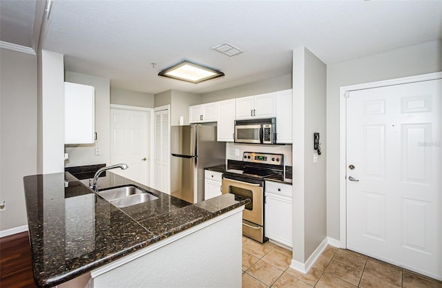 kitchen featuring stainless steel appliances, sink, white cabinets, light tile patterned flooring, and kitchen peninsula