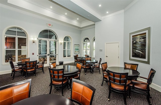 dining room featuring a towering ceiling, dark colored carpet, and french doors