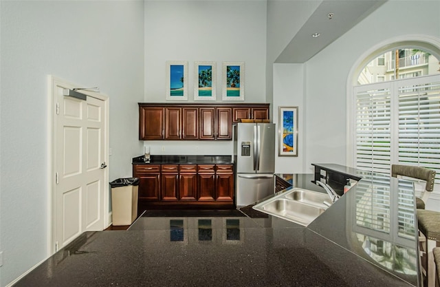 kitchen featuring a towering ceiling, stainless steel fridge, and sink