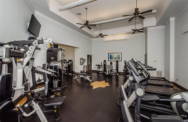 exercise room with a high ceiling, a raised ceiling, and ornamental molding