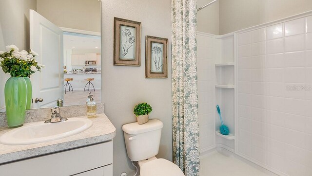 bathroom with curtained shower, vanity, and toilet