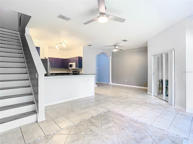 kitchen featuring ceiling fan, light tile patterned floors, kitchen peninsula, and stainless steel refrigerator