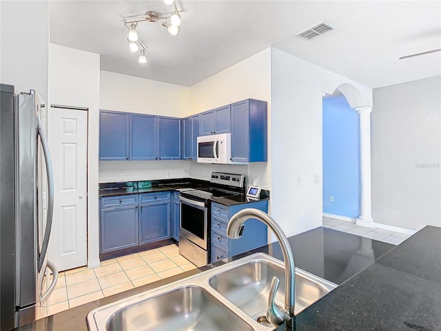 kitchen featuring blue cabinetry, sink, decorative columns, light tile patterned flooring, and appliances with stainless steel finishes