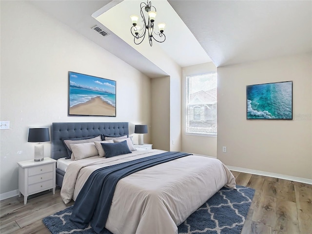 bedroom featuring lofted ceiling, light hardwood / wood-style floors, and a notable chandelier