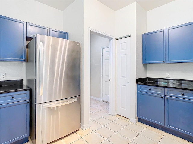 kitchen with blue cabinetry, stainless steel fridge, and light tile patterned floors