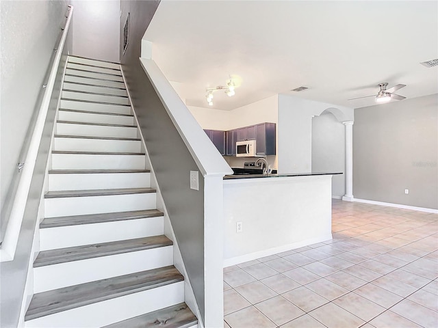 stairs with decorative columns, ceiling fan, tile patterned flooring, and sink