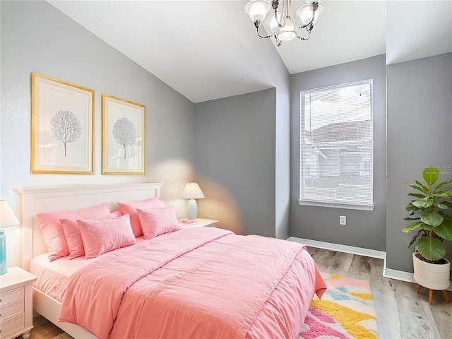 bedroom with light hardwood / wood-style flooring, lofted ceiling, and an inviting chandelier