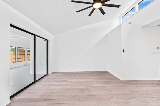 spare room featuring a textured ceiling, light hardwood / wood-style flooring, ceiling fan, and lofted ceiling