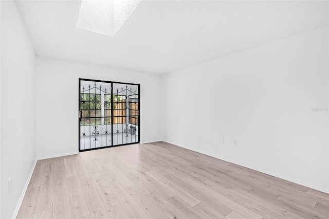 empty room with a skylight and light hardwood / wood-style flooring