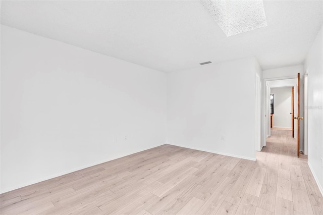 empty room with light wood-type flooring and a skylight