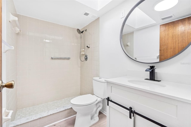 bathroom featuring vanity, toilet, hardwood / wood-style floors, and tiled shower