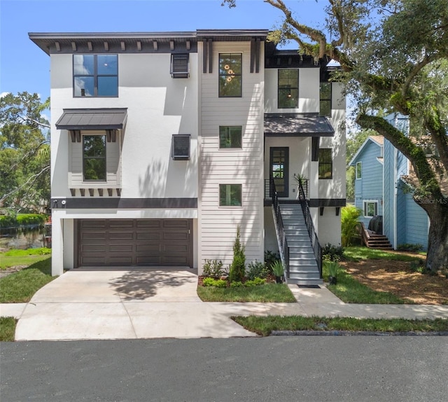 contemporary house featuring a garage, driveway, stairs, and stucco siding