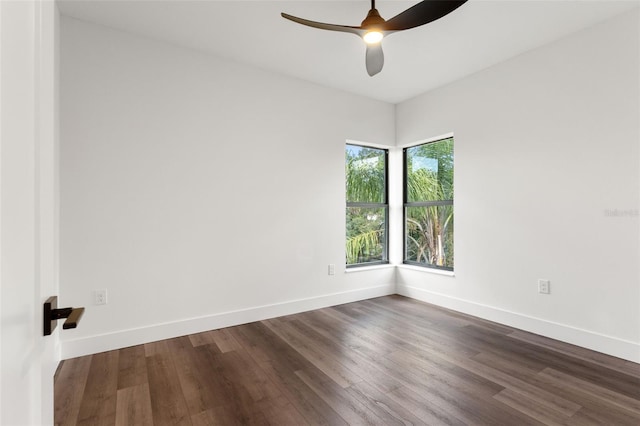 spare room featuring dark wood-style flooring, ceiling fan, and baseboards