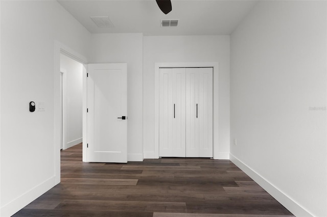 unfurnished bedroom featuring a closet, dark hardwood / wood-style floors, and ceiling fan