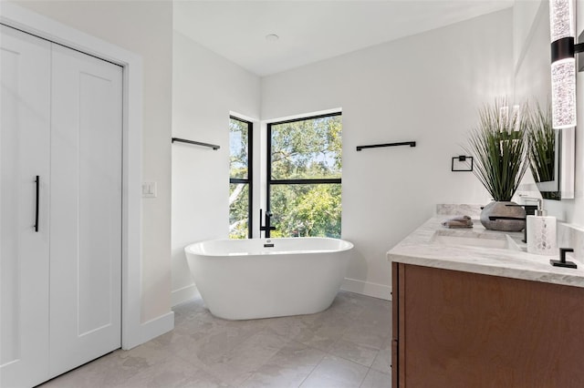 full bath featuring a soaking tub, a sink, baseboards, and double vanity