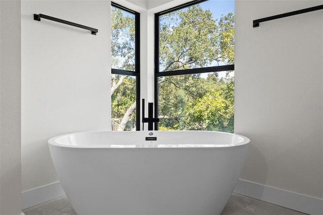 bathroom with baseboards, a soaking tub, and tile patterned floors