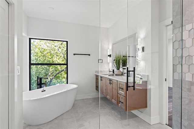 bathroom with a sink, baseboards, a freestanding bath, marble finish floor, and double vanity